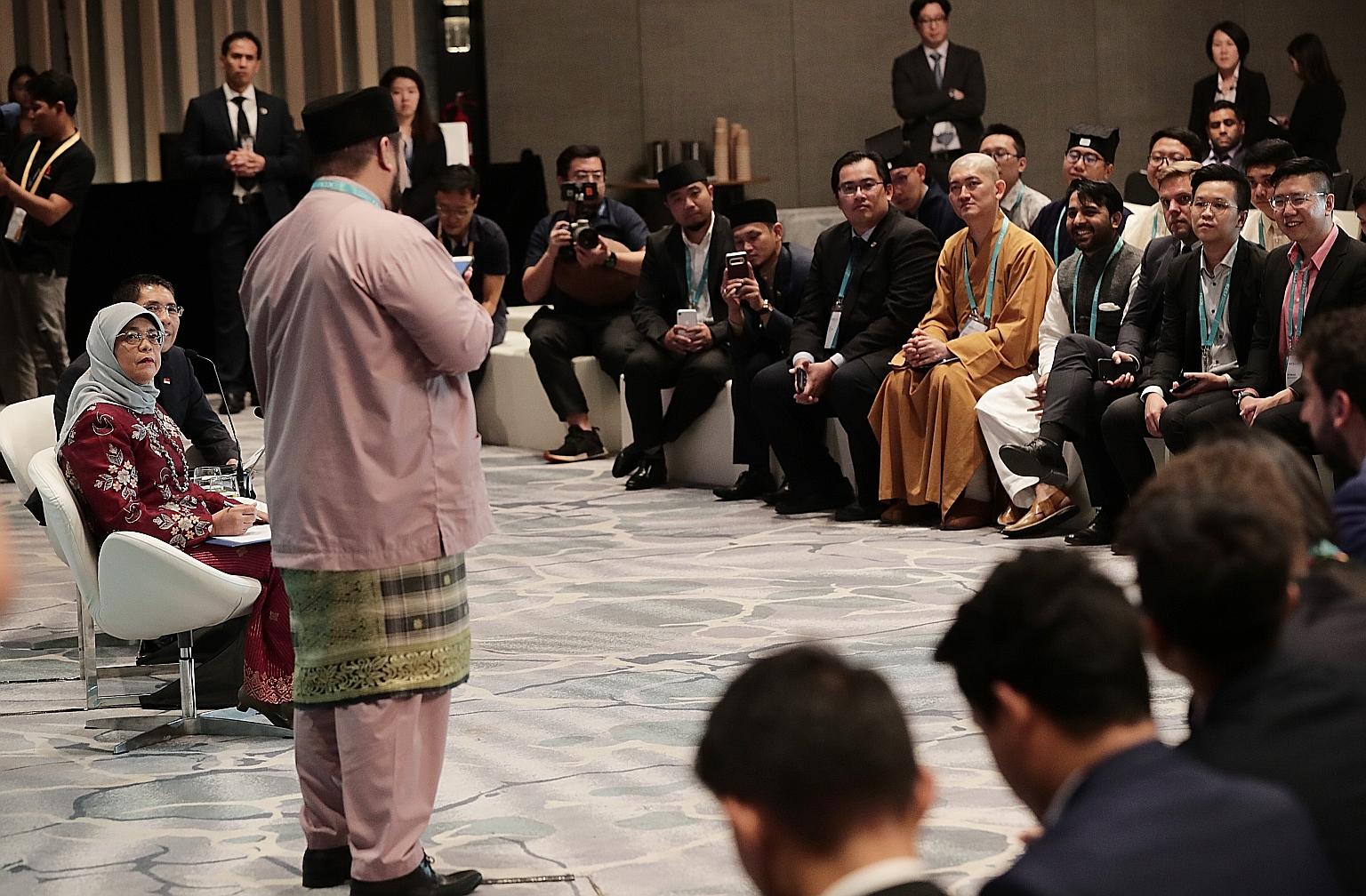 President Halimah Yacob, Senior Minister of State for Defence and Foreign Affairs Maliki Osman (seated on the left) and delegates of the Young Leaders' Programme listening to Bruneian delegate Md Haziq Hisyam Md Zaki at the International Conference o