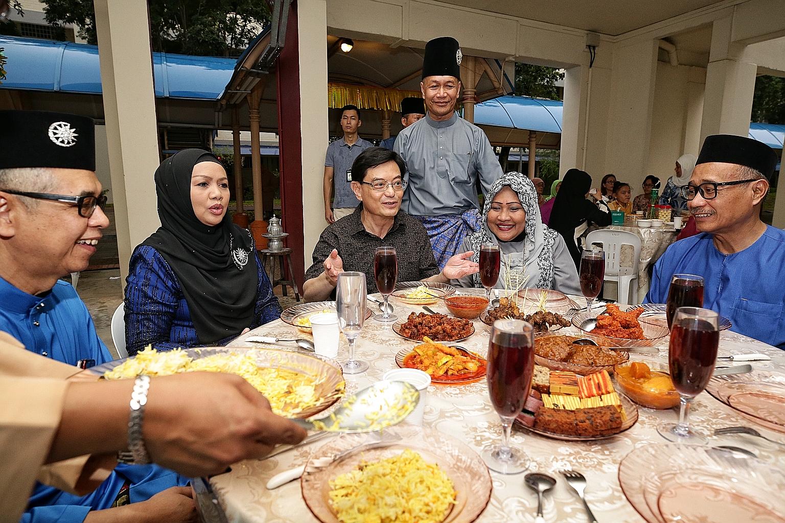 Deputy Prime Minister Heng Swee Keat joining Mr Abas Abdul Rahman (standing) and his wife, Madam Ratnah Mohari, at the couple's annual Hari Raya dinner at the void deck outside their ground-floor Tampines flat yesterday. Mr Heng, an MP for Tampines G