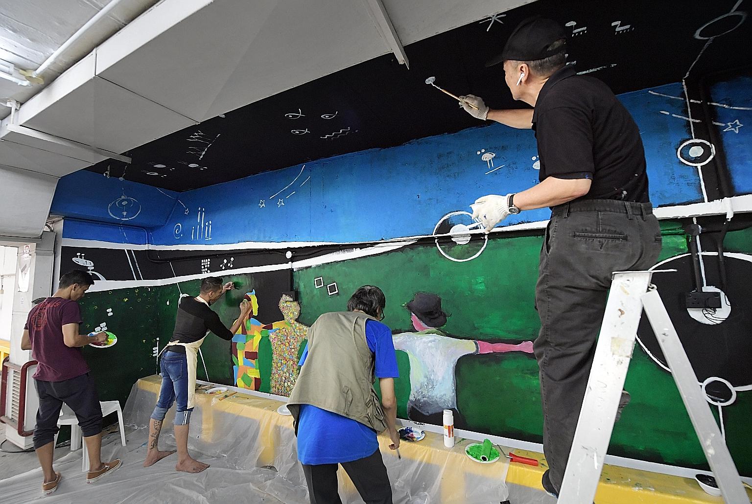 Renowned sculptor Sun Yu-li (far right) and a group of former offenders giving a fresh look to Parklane Shopping Mall's carpark by painting a mural on one of its walls yesterday. Called Turning Points, the mural was designed and painted by Sun, artis