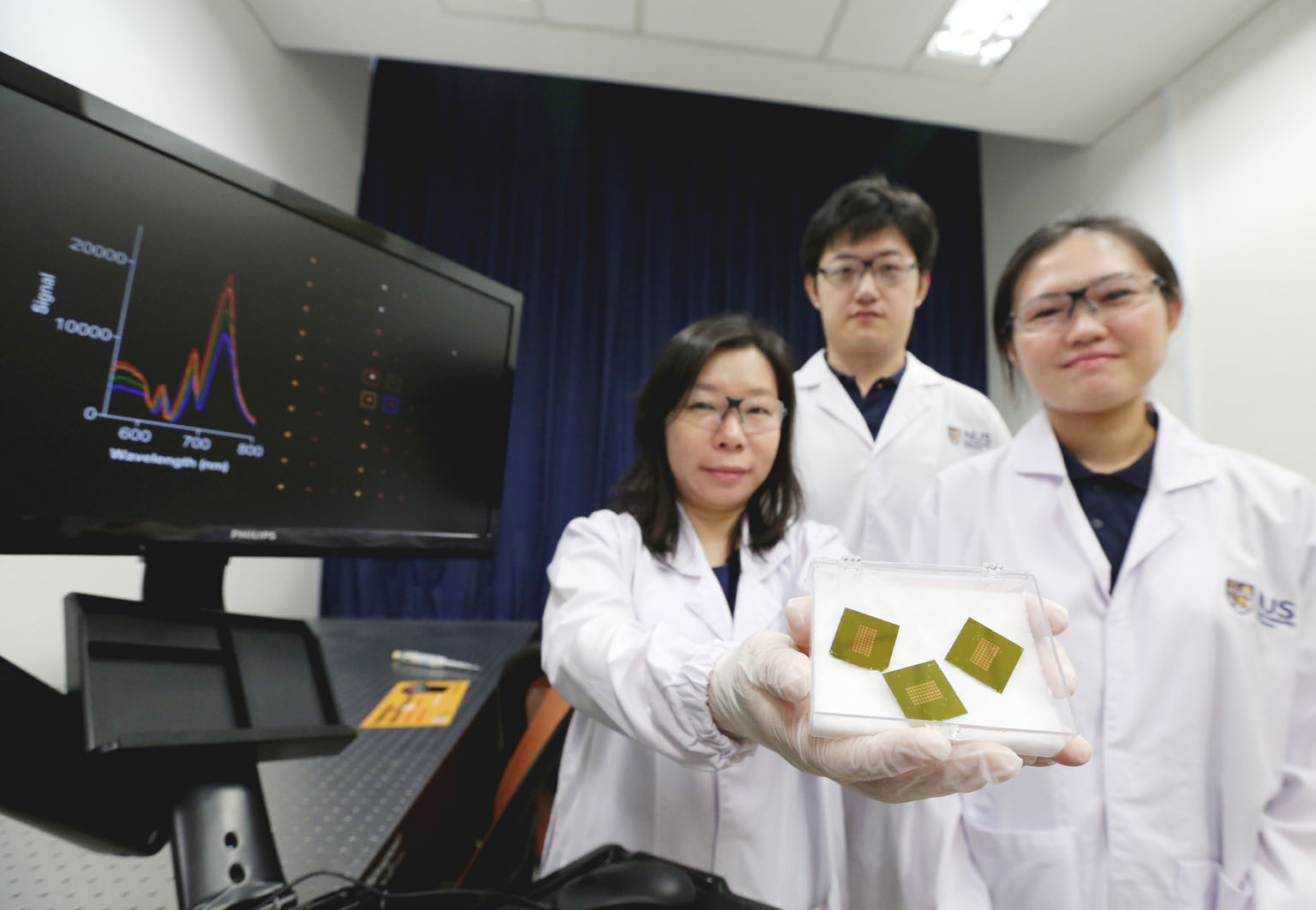 The NUS researchers (from far left) Assistant Professor Shao Huilin with doctoral students Zhang Yan and Carine Lim behind the test that can detect a molecule indicating early-stage Alzheimer's disease, the most common cause of severe dementia.