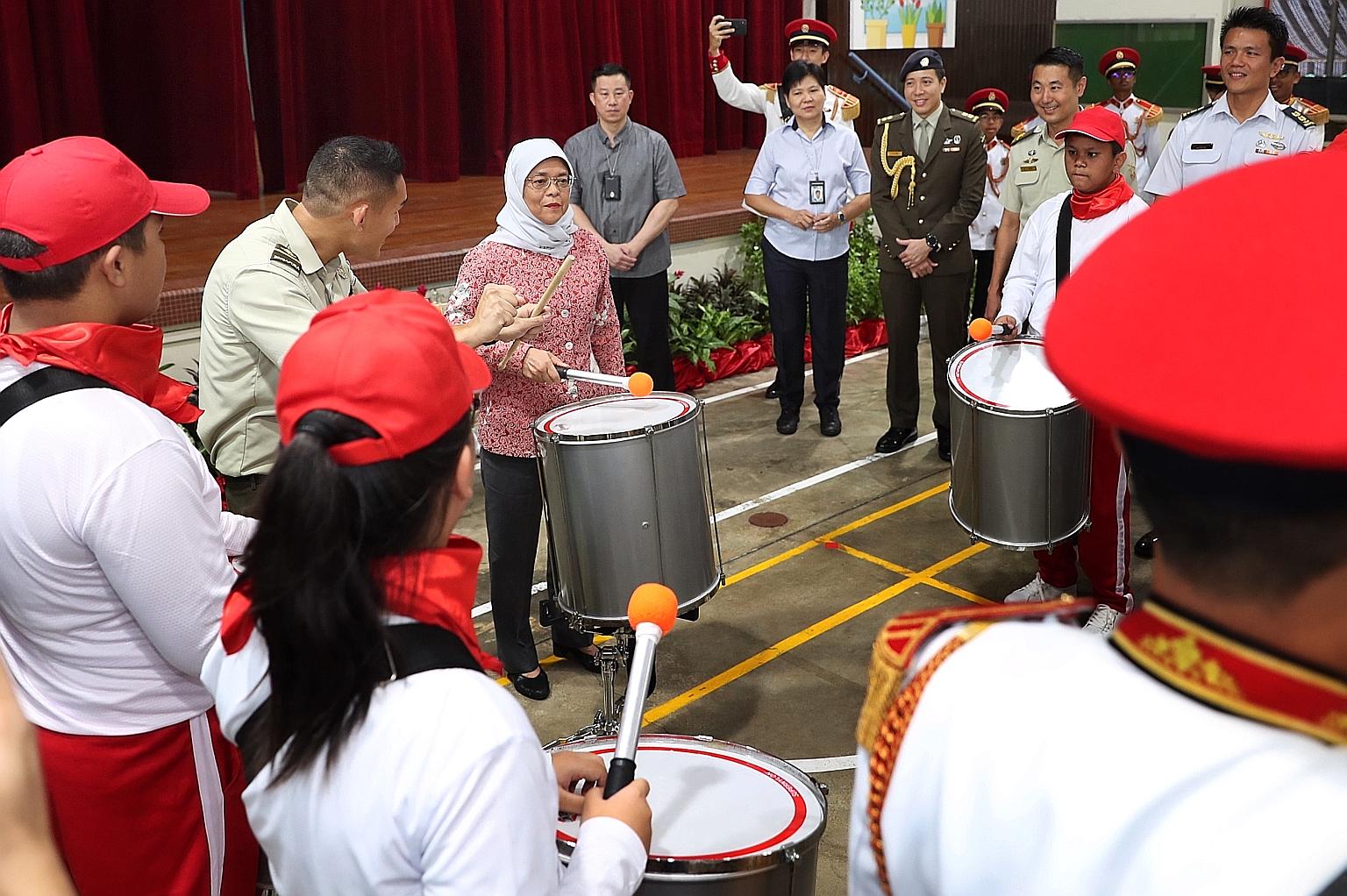 President Halimah Yacob trying out drumming with performers from a combined drum band for this year's National Day Parade, at APSN Tanglin School yesterday. The band consists of 24 participants from APSN Tanglin - a special education school for those