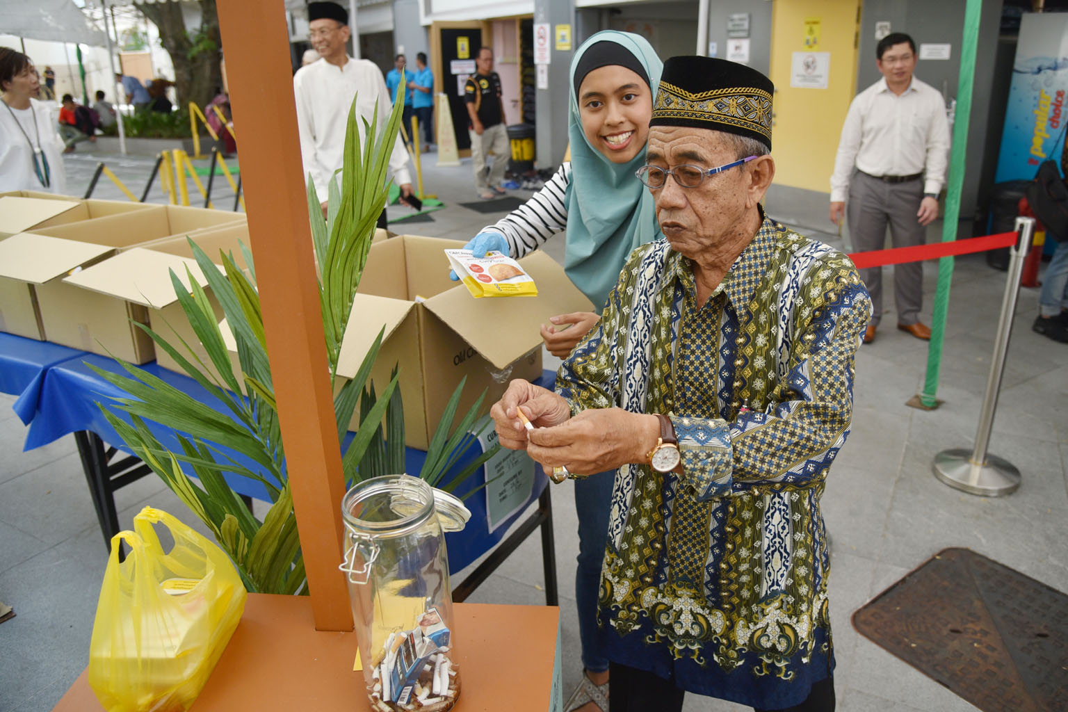 Mr Wahab Mohamed, 77, giving up his cigarette in exchange for a curry puff at Sultan Mosque yesterday. Until mid-October, smokers who visit Puff For A Puff booths at 22 partner mosques can trade cigarettes for free curry puffs, before choosing to joi