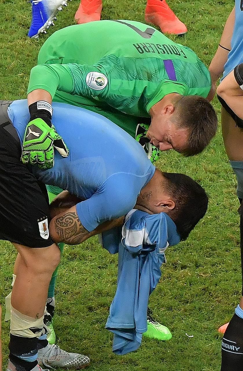 Left: Peru goalkeeper Pedro Gallese saving Uruguay's first penalty when Luis Suarez shoots straight into him at Arena Fonte Nova Stadium in Salvador, Brazil, on Saturday. Above: A distraught Suarez is comforted by Uruguay goalkeeper Fernando Muslera.