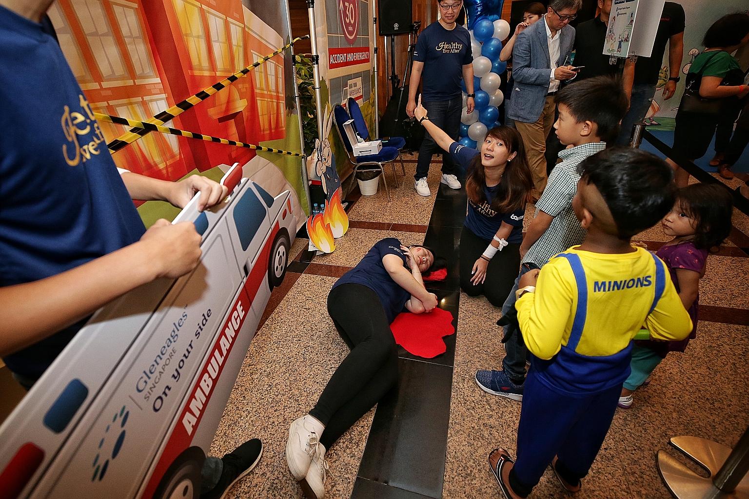 Children learning about giving first aid in an "emergency" situation at Gleneagles Hospital's 60th Anniversary Carnival. The hospital has pledged to raise funds to help 60 beneficiaries of The Straits Times School Pocket Money Fund with $60 a month f