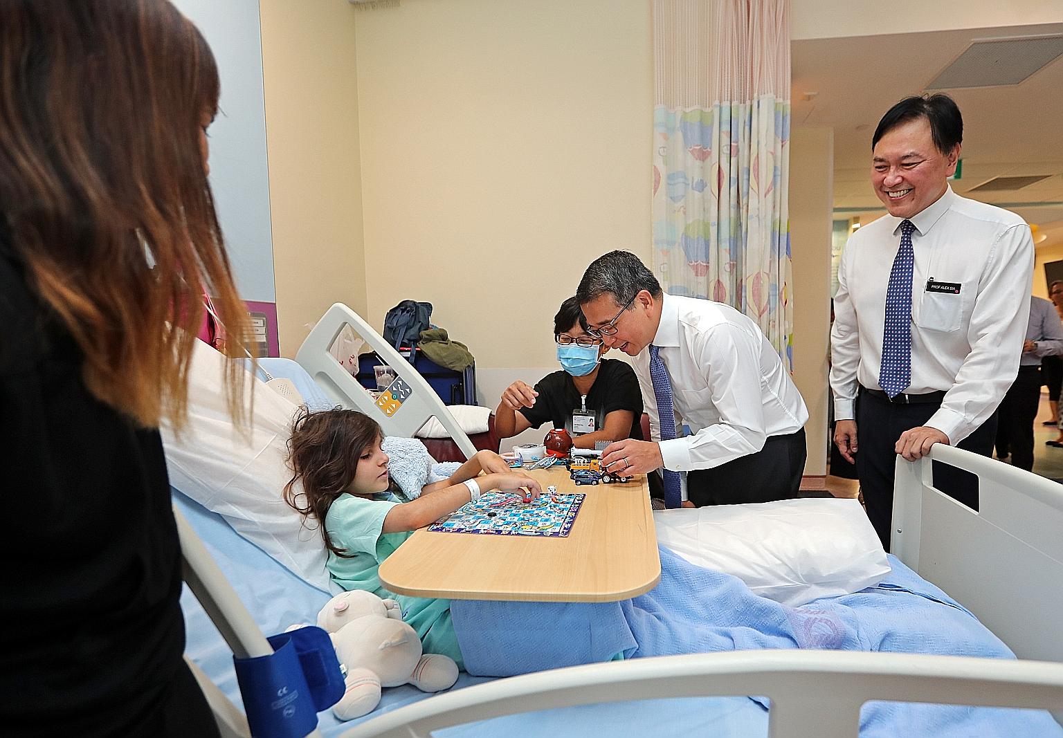 Senior Minister of State for Health Edwin Tong with Svea Nadia Hertzman, eight, at the children's ward of KK Women's and Children's Hospital (KKH) yesterday. He was accompanied by KKH chief executive Alex Sia.