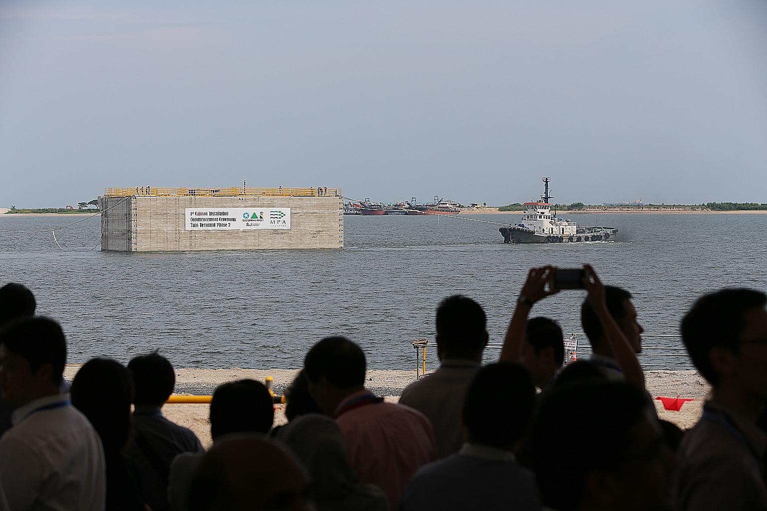 A tugboat pulling into place yesterday the first of 227 caissons needed to construct the wharf for the second phase of the Tuas mega port. ST PHOTO: ONG WEE JIN