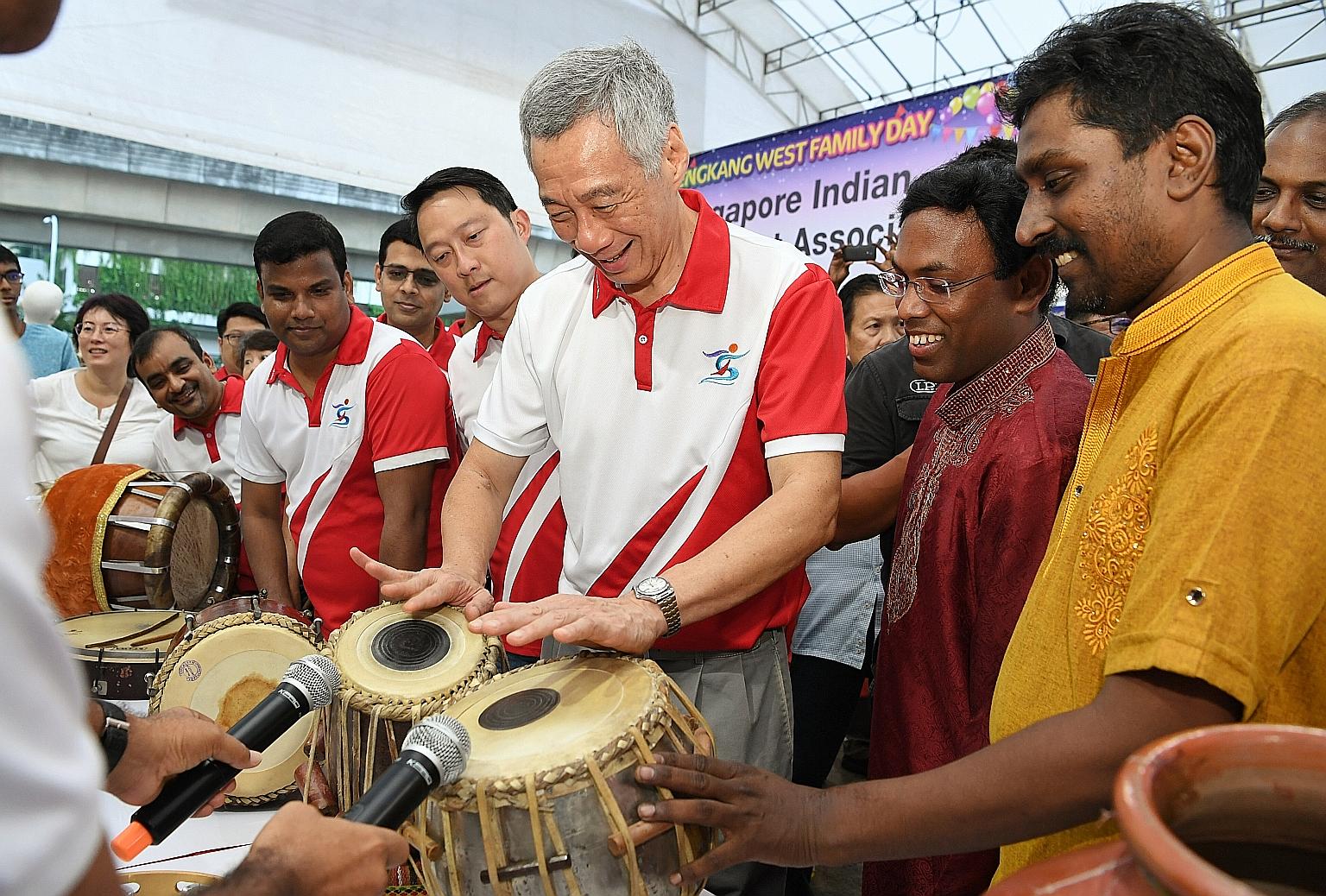 Prime Minister Lee Hsien Loong trying out the tabla, a traditional Indian percussion instrument, yesterday at the Sengkang West Family Day, as Senior Minister of State for Health and Transport, and MP for Sengkang West, Dr Lam Pin Min, looks on. With