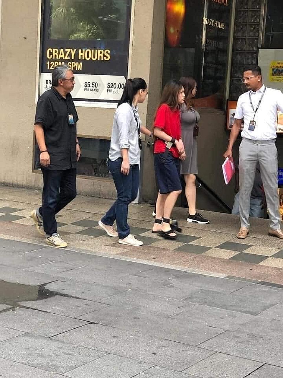 Murder accused Natalie Siow Yu Zhen (in red) being taken back to the crime scene at Orchard Towers. She is among the four still accused of murdering Mr Satheesh Noel Gobidass, who died following a brawl. LIANHE ZAO BAO FILE PHOTO