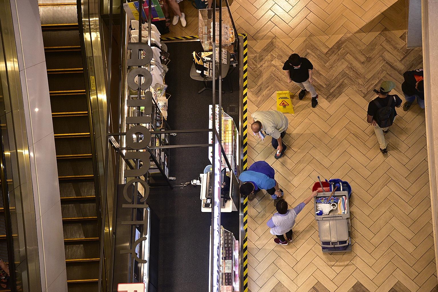 Workers cleaning up the area in basement two of Ngee Ann City, where the man landed after falling several floors. The 35-year-old died later of his injuries. ST PHOTO: DESMOND WEE