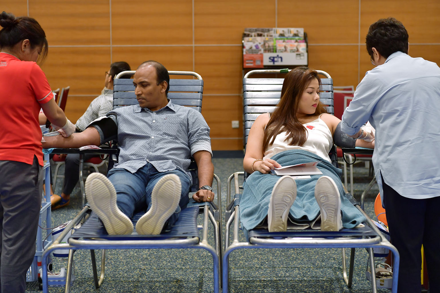 Singapore Press Holdings staff Sajo Kuttikkat Johny, senior manager (Adtech), and Nisha Basand Ram, assistant manager of marketing and circulation, donating blood during SPH Red Apple Day at the SPH Auditorium yesterday. Some 119 units of blood were