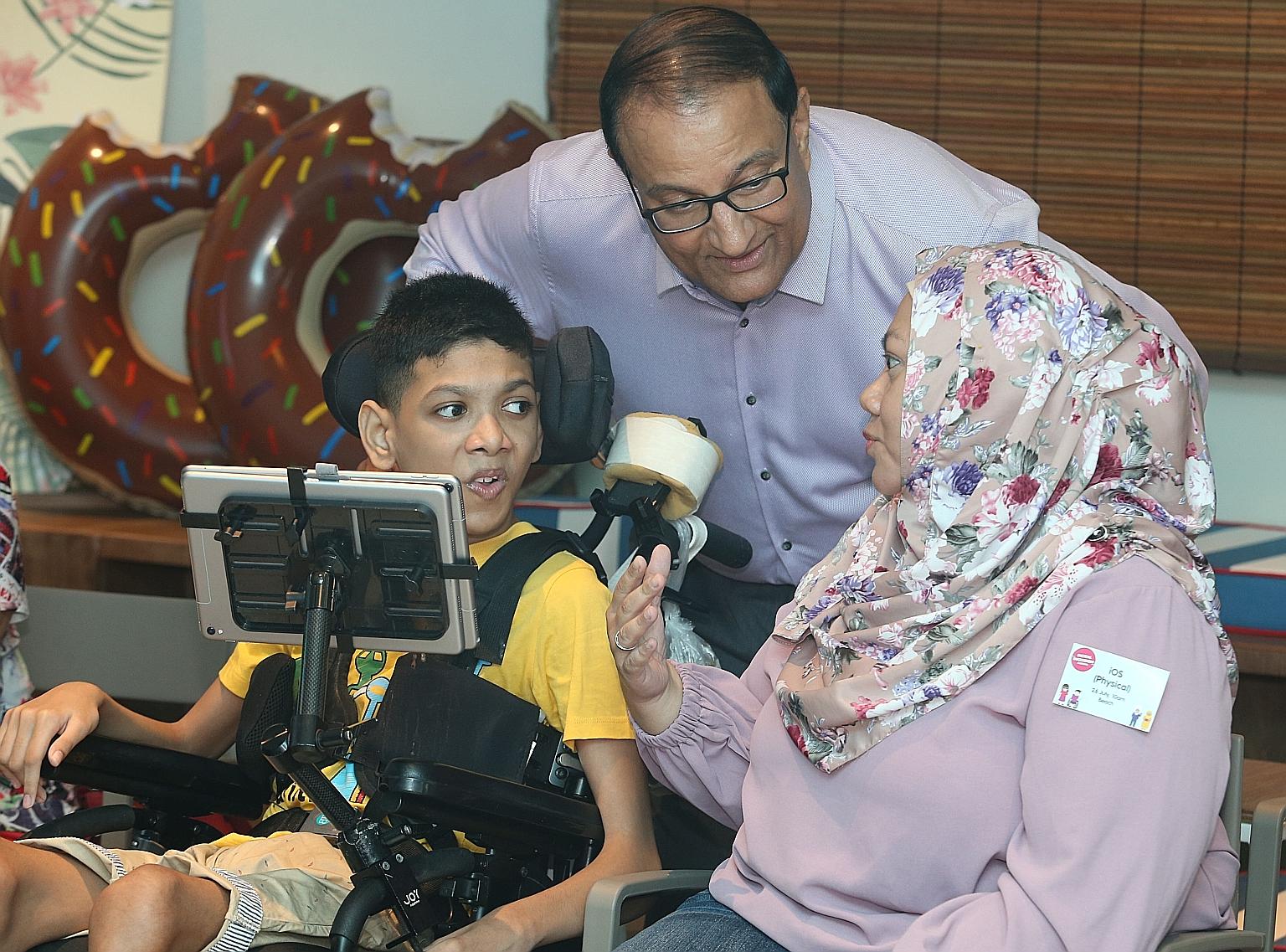 Madam Siti Fadillah Mohamed Noor, 41, and her son Muhammad Sayfullah Mohamad Sahrin, 16, chatting with Minister for Communications and Information S. Iswaran at the Digital Inclusion Festival yesterday. The teenager, who has quadriplegic cerebral palsy, a