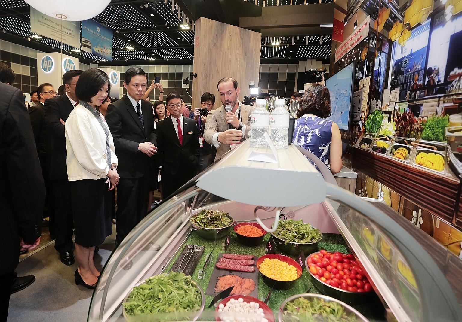 (From left) Senior Minister of State for Communications and Information Sim Ann, Minister for Trade and Industry Chan Chun Sing and SCCCI president Roland Ng visiting the Singtel booth demonstrating the use of IoT Thermo Track, a suite of sensors tha
