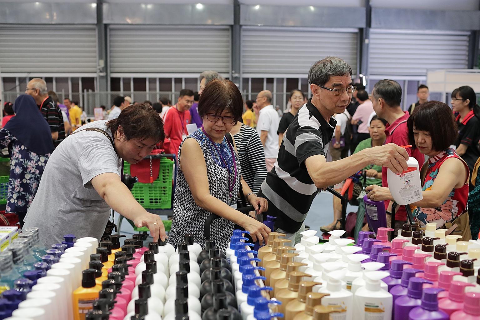 Tampines residents making their selection at a pop-up supermarket at Arena@OTH yesterday during the launch of an initiative offering discounted groceries to lower-and middle-income families for the next year. 