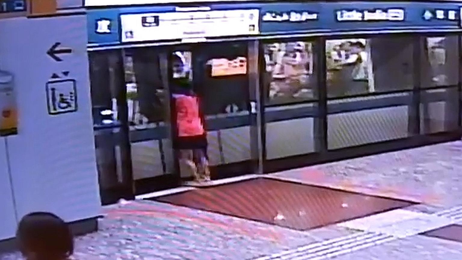 In a screen grab of a video shared on social media, a woman is seen prising open the platform doors before attempting to force open the train doors. The clip also shows commuters trying to help her.