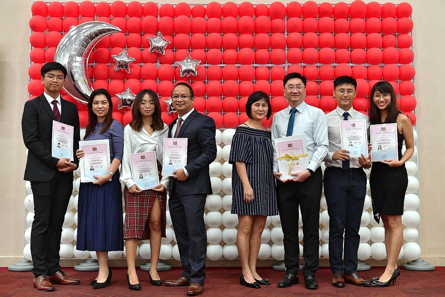 Two families were among the 149 people who became new citizens yesterday. They are (from far left) the Dimalantas - Allen; his mother Michelle Anne Dimalanta; sister Anne; and father Alvin Paras Dimalanta - and the Lams - Ms Josephine Go, who is Sing