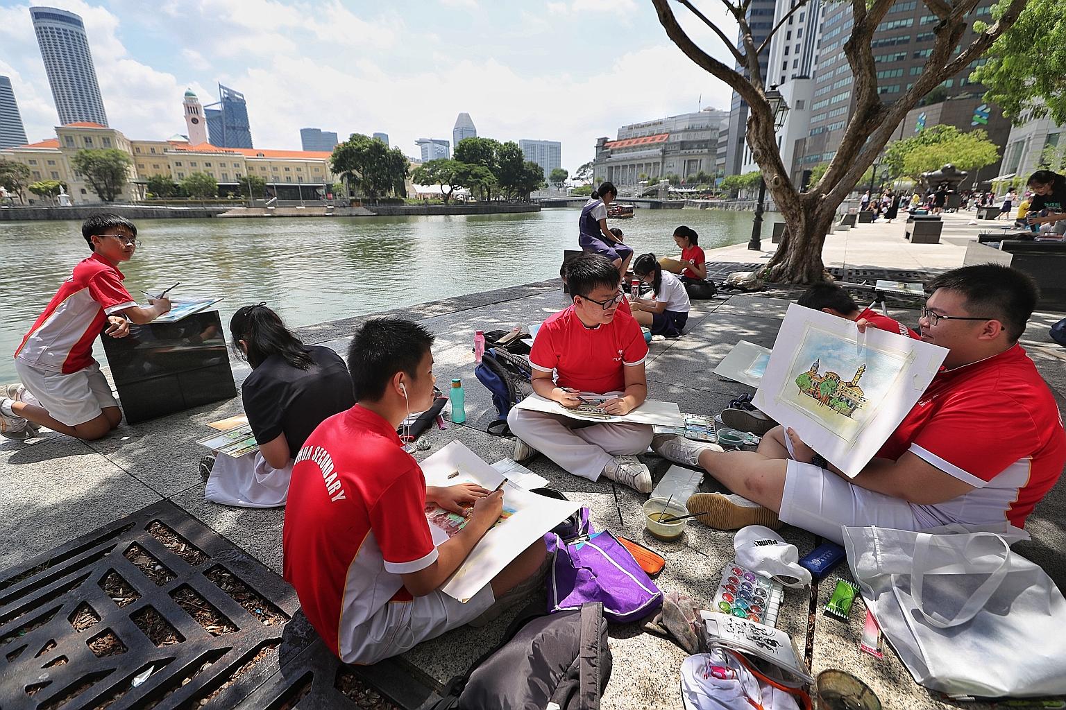 Fuhua Secondary School student Donovan Dua, 14, showing schoolmates Zou Muyan (centre), 15, and Kwa Jun Hao, 14, his painting of buildings around the Singapore River.