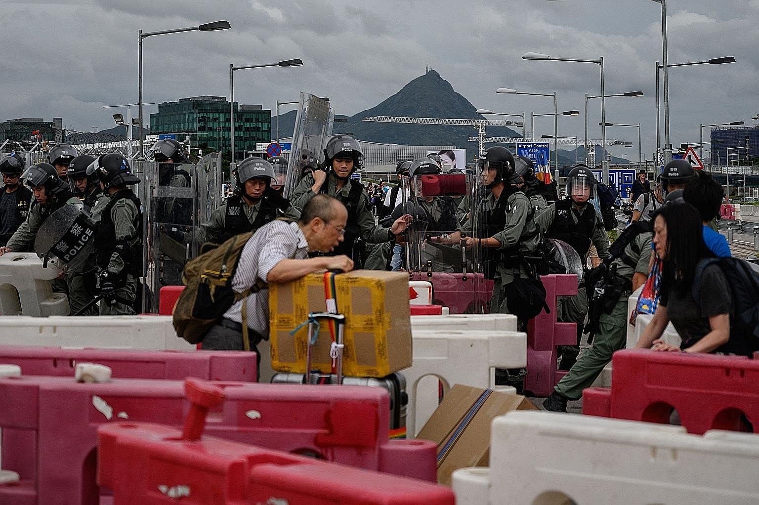 Hong Kong police removing barricades set up on the road by protesters as passengers walked with their luggage to Hong Kong International Airport yesterday. Thousands of anti-government protesters choked routes leading to the airport yesterday, buildi
