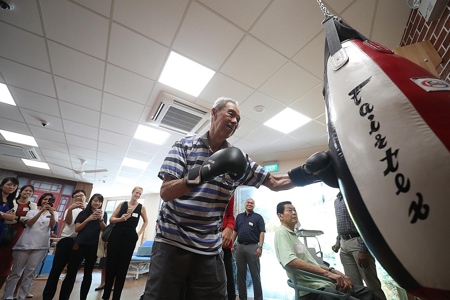 Mr Ho Ah Eng throwing punches at a punching bag at the Telok Blangah Senior Care Centre's rehab gym. Mr Ho, 81, who has an unsteady gait and lower-limb injury, says the weekly boxing classes at the centre have helped improve his balance and strength.