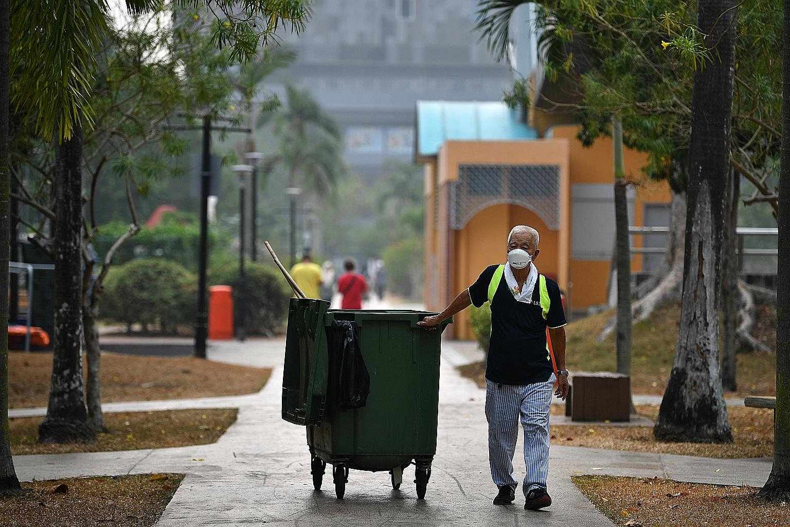Cleaner Ng Siew Chuan, 78, wearing a face mask on the job at Tampines Central Park yesterday at around 9am. The 24-hour PSI reading in the eastern part of Singapore was 109 at 8am yesterday and the one-hour PM2.5 reading was 96. ST PHOTO: LIM YAOHUI