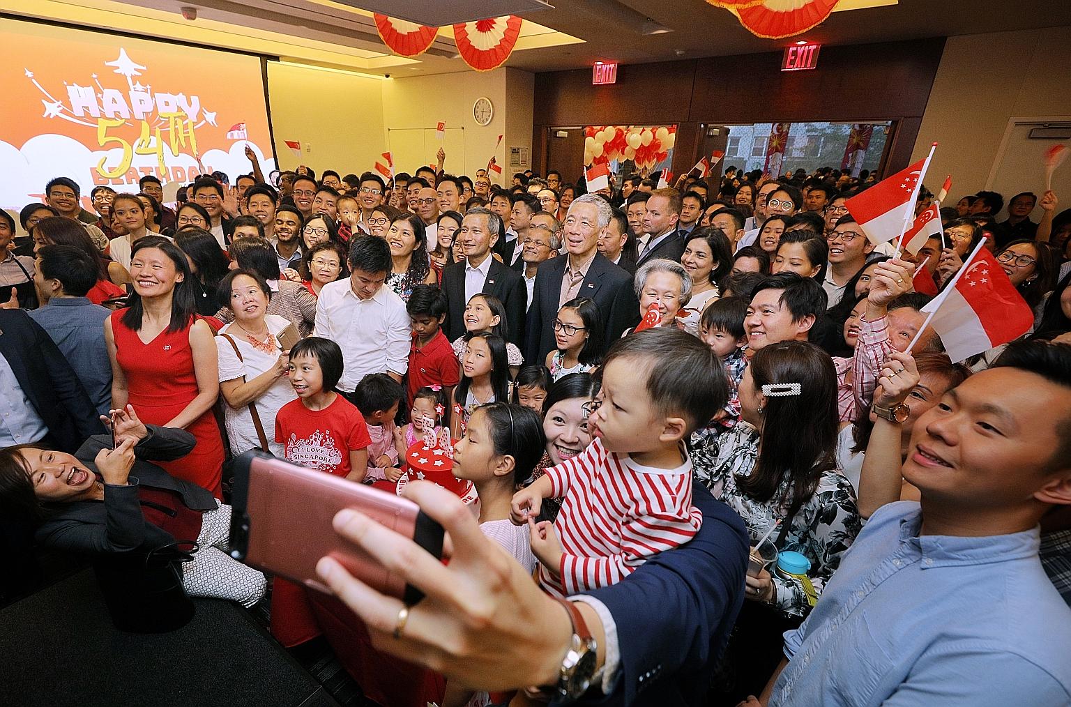 Prime Minister Lee Hsien Loong, flanked by Mrs Lee and Foreign Minister Vivian Balakrishnan, taking photographs with Singaporeans and their families at the National Day reception at the Permanent Mission of the Republic of Singapore to the United Nat