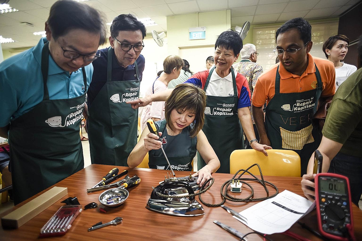 Dr Amy Khor, Senior Minister of State for the Environment and Water Resources, working on an electrical appliance at the launch of a meet-up site to fix damaged goods yesterday. Beside her are (from left) YTL PowerSeraya chief executive John Ng, YTL