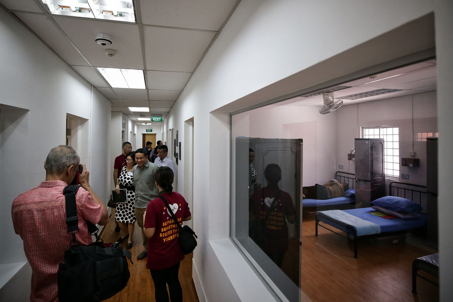 Senior Parliamentary Secretary for Health and Home Affairs Amrin Amin (in grey) yesterday touring the sleeping area of Transit Point, a shelter run by New Hope Community Services.