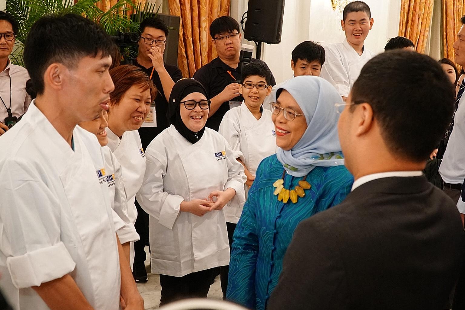President Halimah Yacob and Minister for Social and Family Development Desmond Lee talking to students from the Association for Persons with Special Needs, one of the beneficiaries of the Community Chest, at the awards event at the Istana yesterday. 
