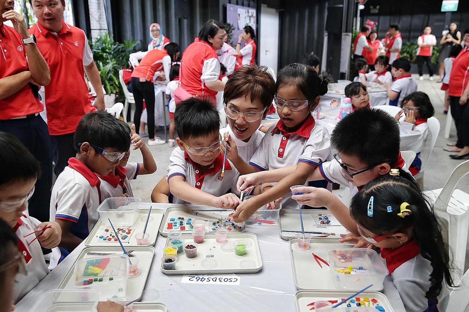 Manpower Minister Josephine Teo helping PCF Sparkletots K2 children Chang Ann Kiet and Rebecca Aarin, both six, in a glass art class at Goodman Arts Centre yesterday.