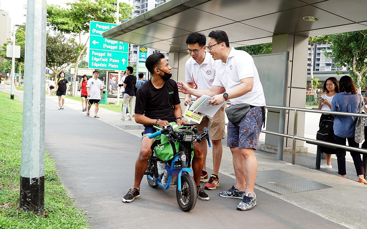 Coraltree Residents Network chairman Andy Ho (centre) and Parc Terraces Residents Network chairman John Yap talking to a personal mobility device user in Punggol about using the device safely and responsibly, as part of the Active Mobility Patrol sch