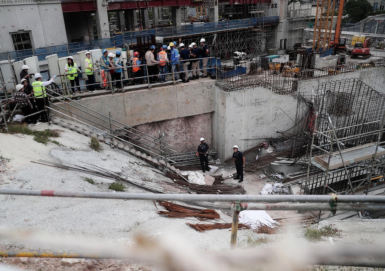 Police officers, with the body of the dead worker (foreground, covered by white sheet), at the work site in Novena yesterday. The Ministry of Manpower said the jib, or horizontal beam, of a tower crane had failed during a lifting operation. The polic