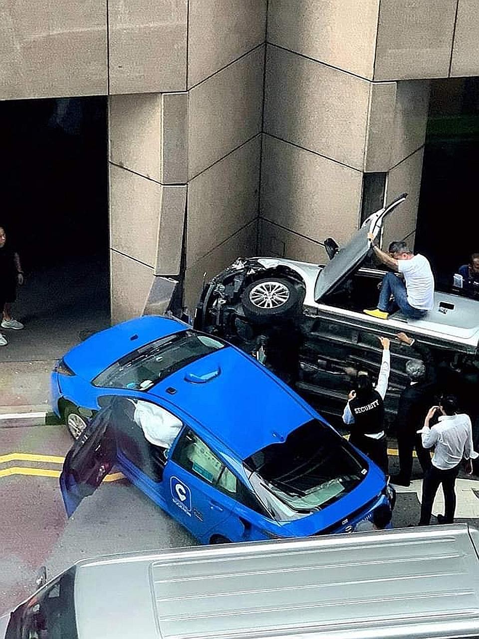 An accident between a taxi and a car yesterday morning resulted in both vehicles lodged in front of the AIA Tower, near Raffles Place MRT station, with the car flipped on its side.