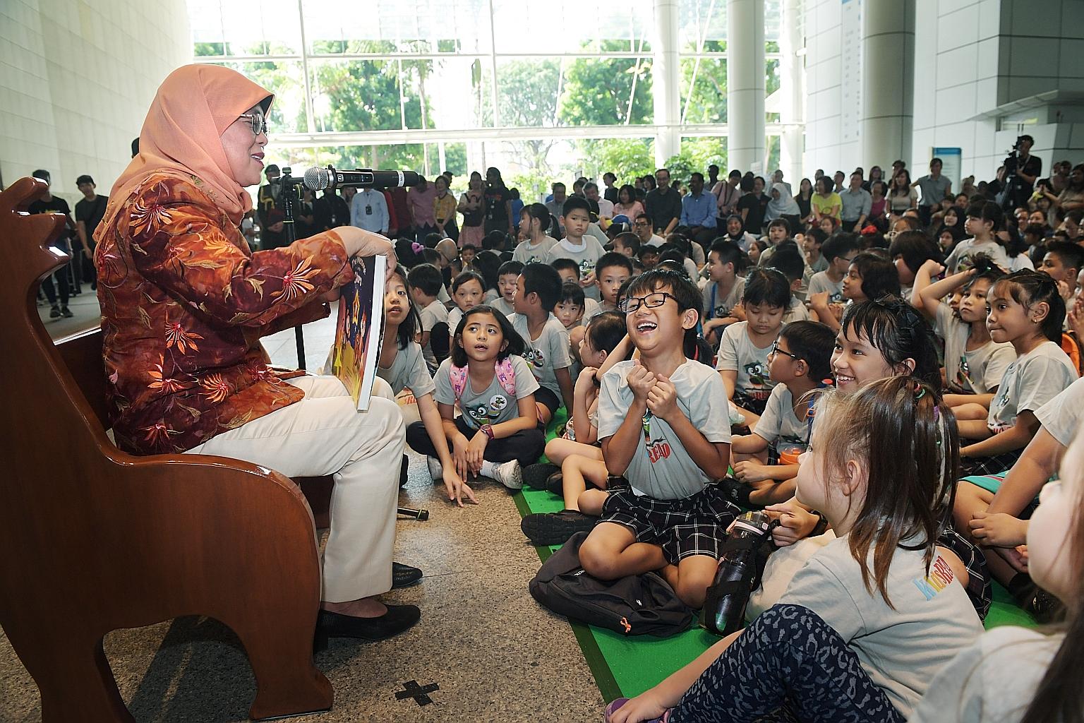 President Halimah Yacob reading a book, The Message In The Stars, to about 230 children, their parents and volunteers at the National Library in Victoria Street yesterday. ST PHOTO: ALPHONSUS CHERN