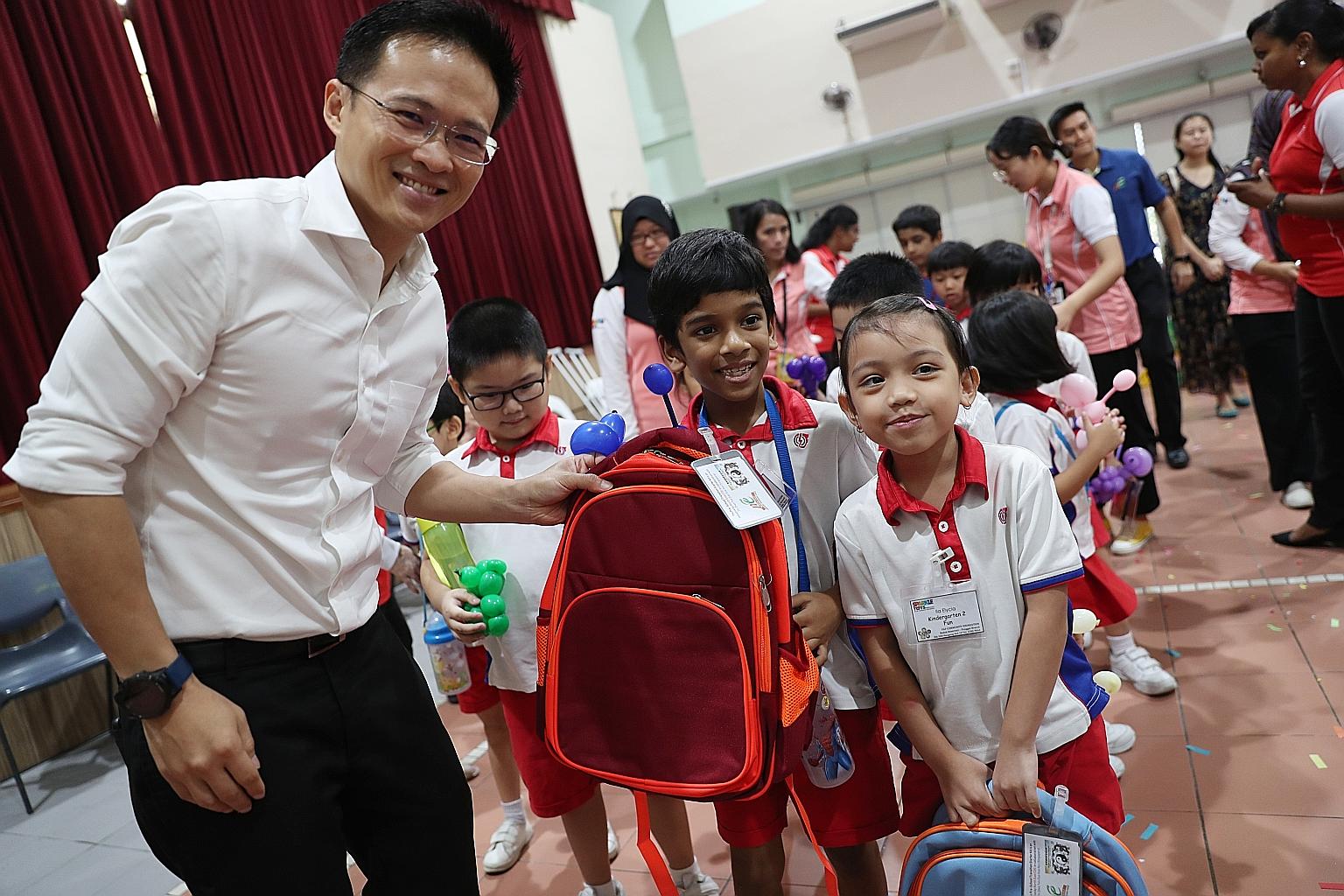 North East District Mayor Desmond Choo giving the Pre-school Transition Starter Kit to PCF Sparkletots children Muhammad Shaqeeq Mohammad Shamsudeen (middle), six, and Ila Elycia Taufeq (right), six, at the launch event in Punggol Community Club yest