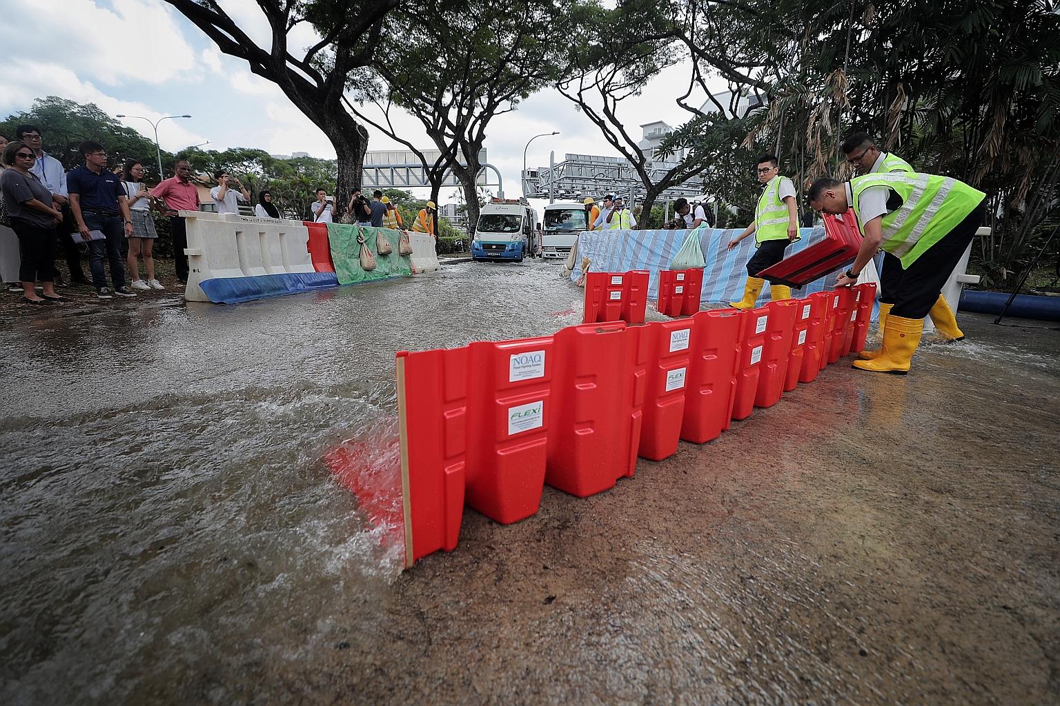New portable flood barriers such as these, seen here at a presentation for the media yesterday, will be deployed in public areas to divert floodwaters so traffic and people can pass during heavy rain. ST PHOTO: GAVIN FOO