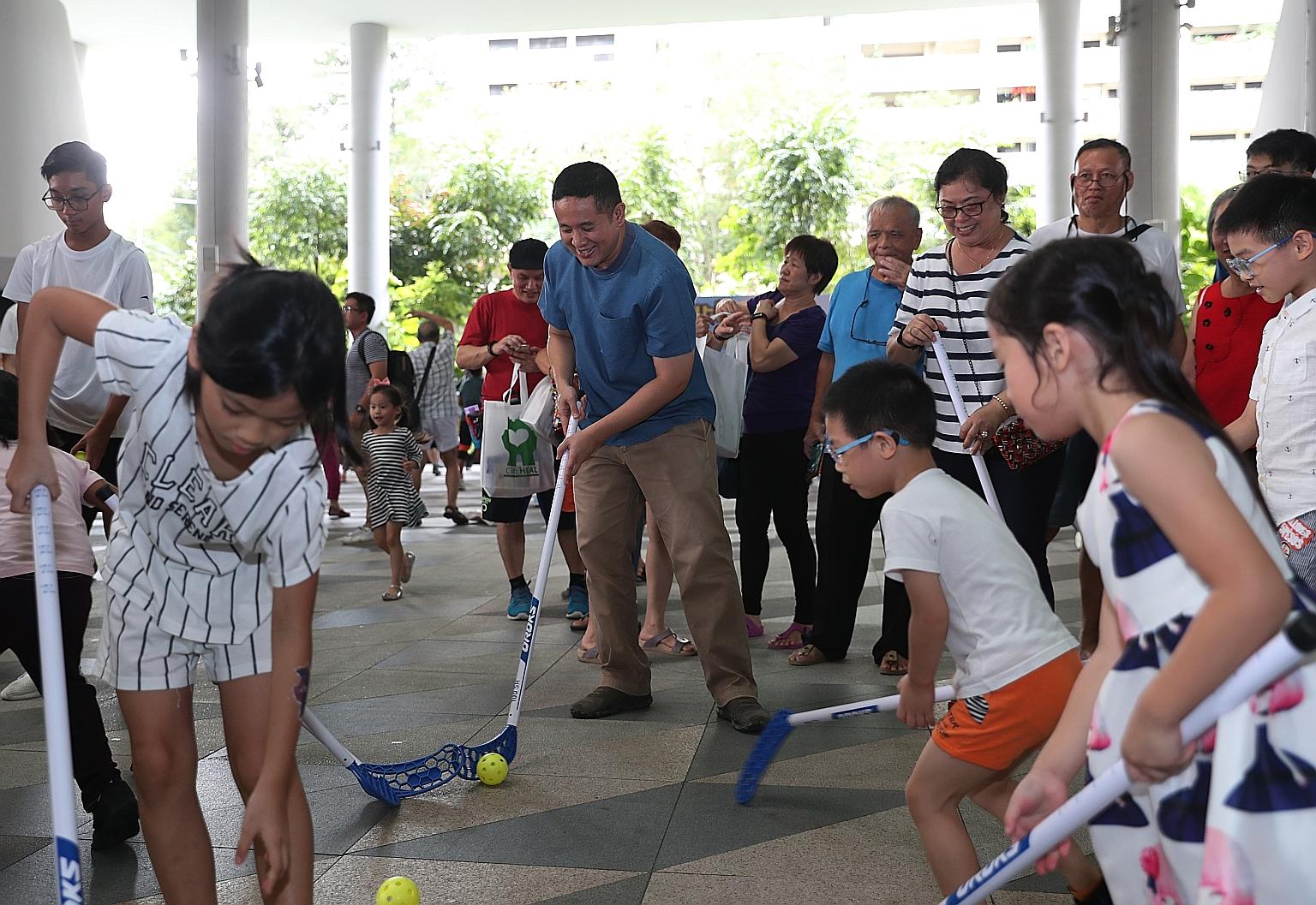 Senior Parliamentary Secretary for Health and Home Affairs Amrin Amin playing floorball with children at the Family Health and Wellness Carnival yesterday.