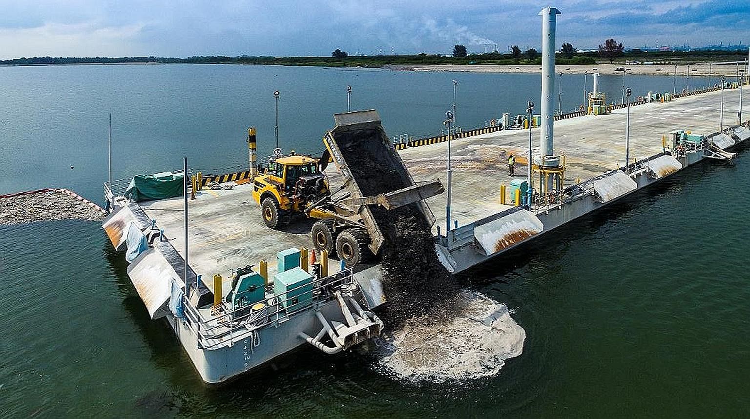 A dump truck discharging ash into Semakau Landfill from the floating platform that was built to mitigate the risk of trucks falling into the dumping area. 