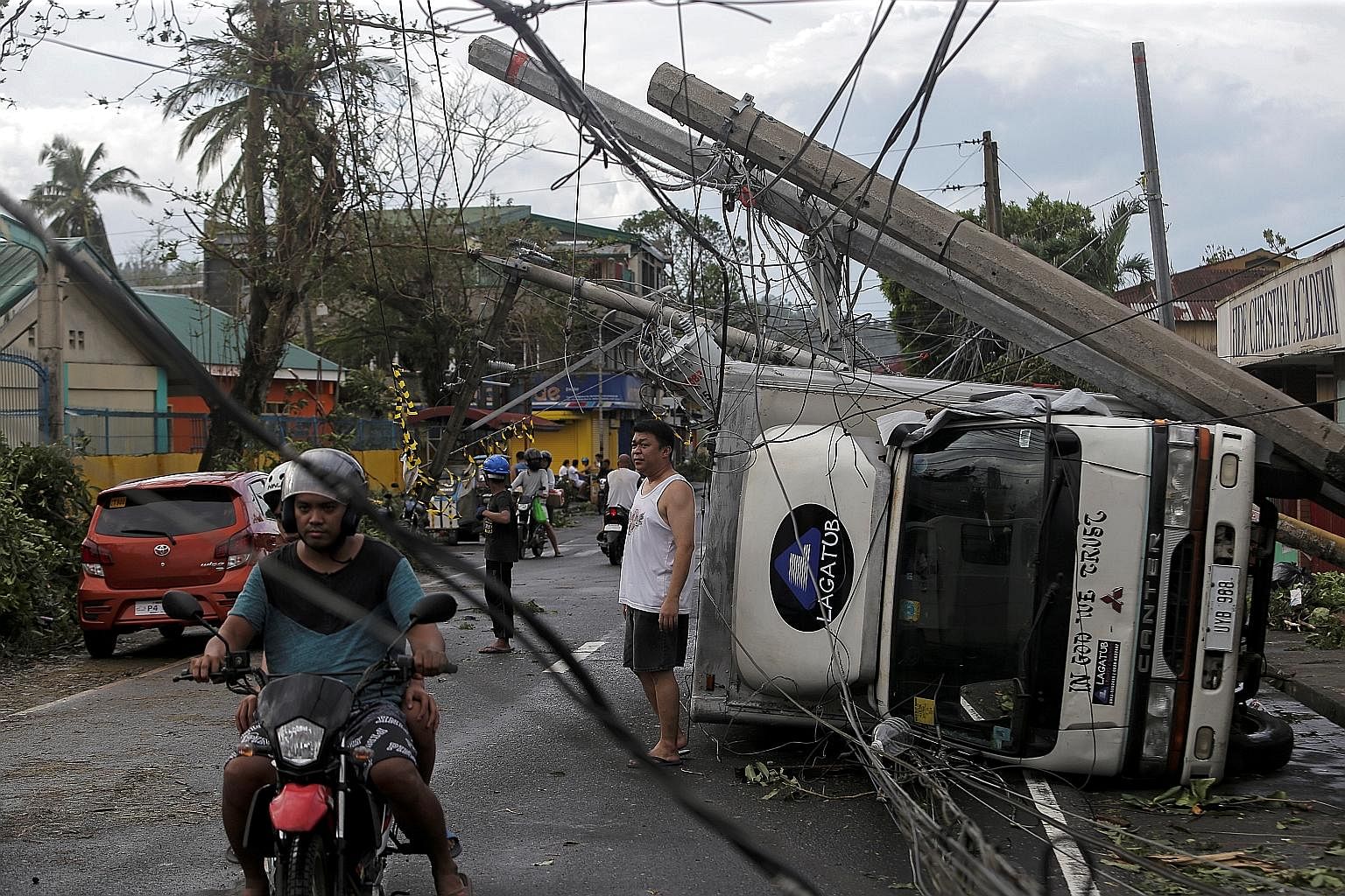 Residents in Camalig town, in the Philippines, going about their lives yesterday amid the damage caused by Typhoon Kammuri. At least four people died in the country but early evacuation of hundreds of thousands of villagers from areas prone to flash 