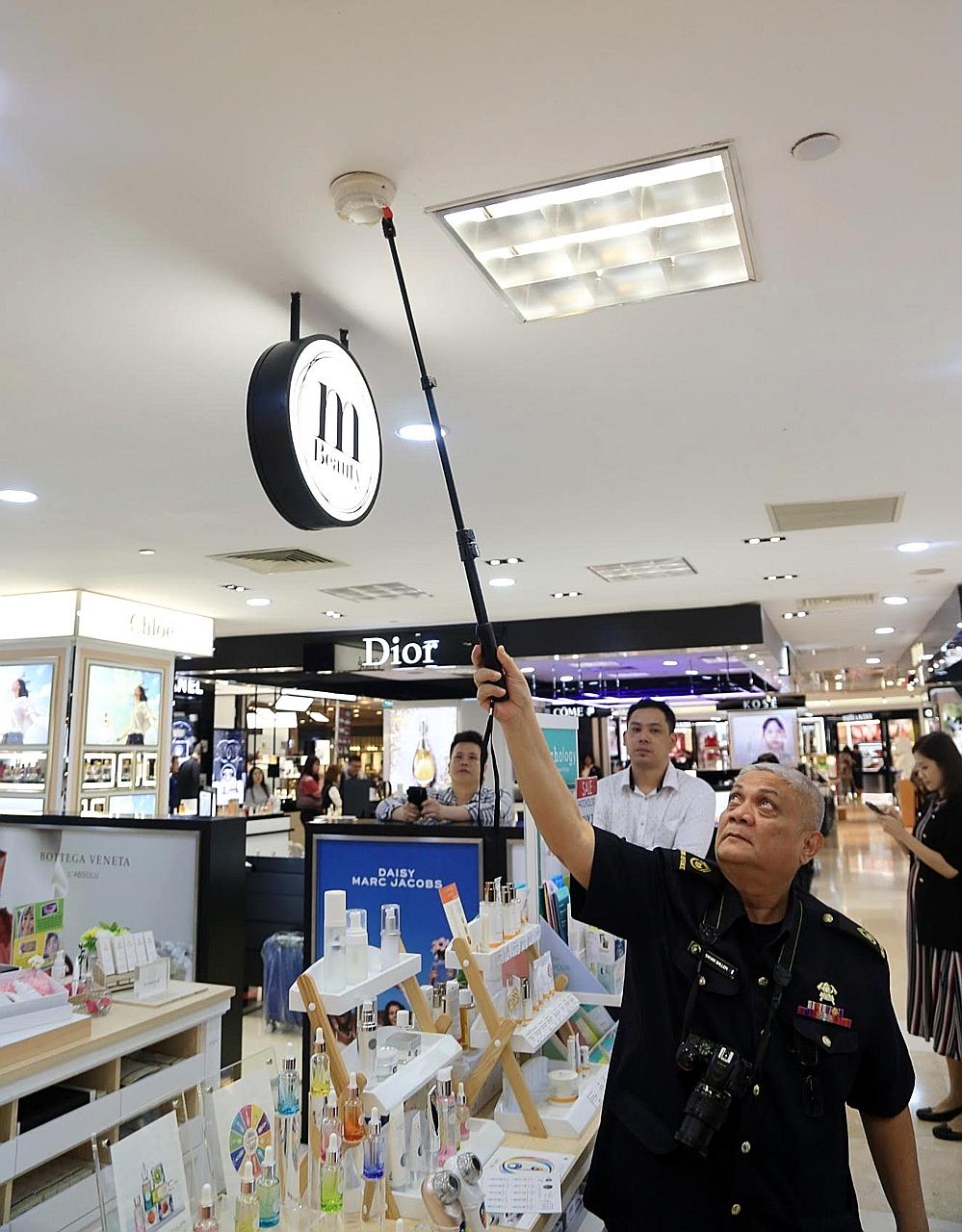 An officer from the Singapore Civil Defence Force inspecting the serviceability of a smoke detector. The force says it is important for places of recreation such as shopping centres and hotels to be mindful of fire safety, with higher footfall expected in