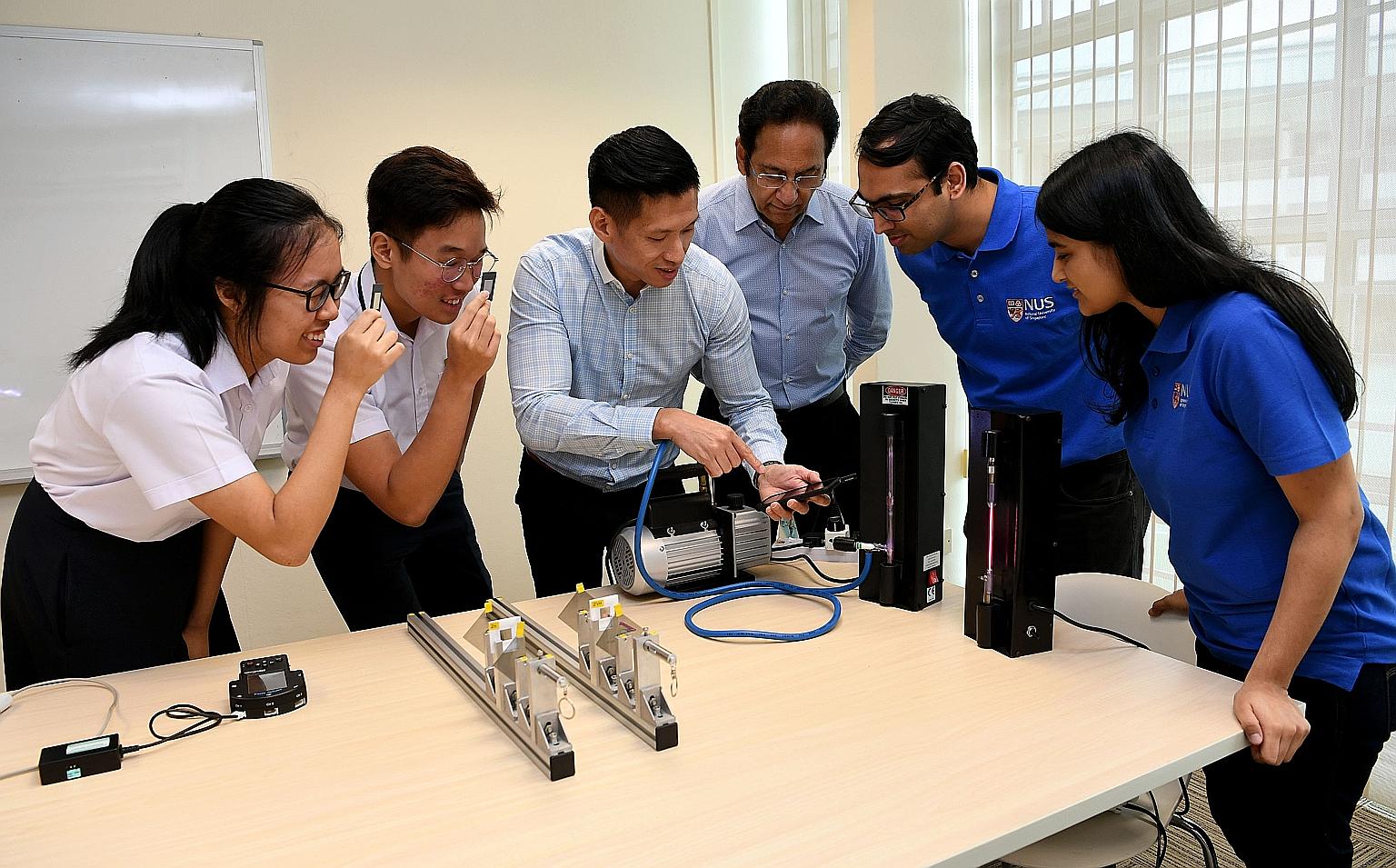 Jurong Pioneer Junior College's head of department for curricular development and innovation Edwin Lim using a mobile phone spectrometer, which measures light wavelengths. With him (from far left) are students Narahda Lim and Haw Jin Yu; Professor Th