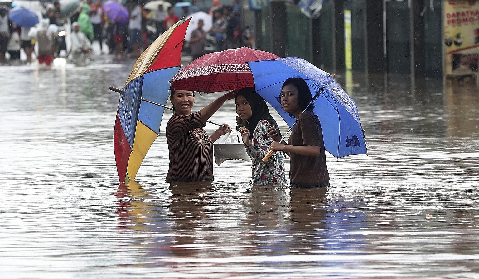 People wading through floodwaters in Jatibening, on the outskirts of Jakarta, yesterday. Electricity was cut off in many of the city's neighbourhoods, with some train lines and an airport also shut.