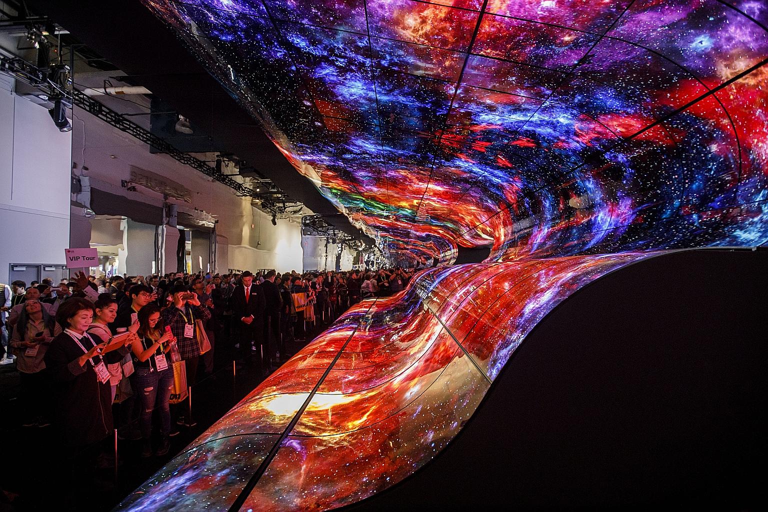 Attendees taking photographs of a curved electronic display wall at the entrance to the LG Electronics booth at last January's CES trade show in Las Vegas. This year's show, starting next week in the same US city, is not expected to feature any break