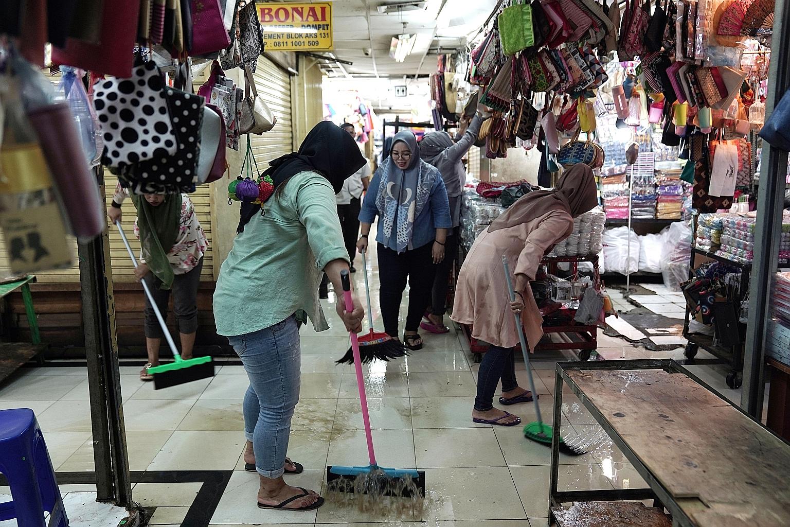 Workers sweeping away flood water outside stores at a shopping centre in the Jatinegara district of Jakarta yesterday.