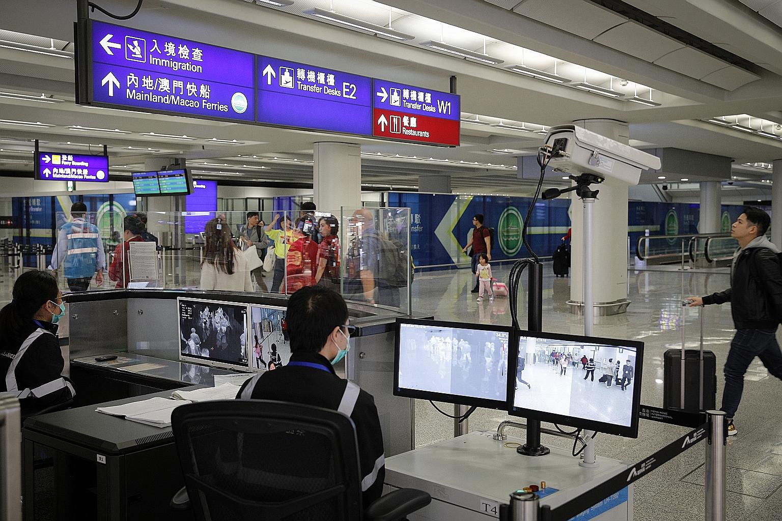 Health surveillance officers using temperature scanners to monitor passengers arriving at Hong Kong International Airport yesterday, amid fears about a mysterious infectious disease that has appeared in China.