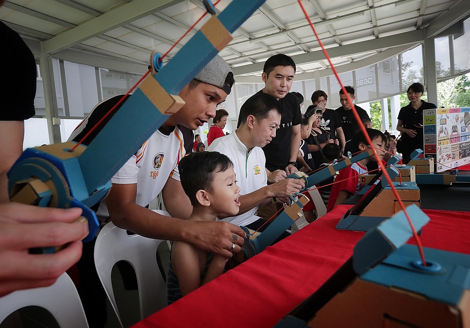 Adviser to Canberra GROs Lim Wee Kiak (seated) trying out a fishing game that uses Nintendo Labo yesterday. The game section was set up by Bountie Technologies as part of a block party organised in conjunction with WeCare @ North West - Service Weeks