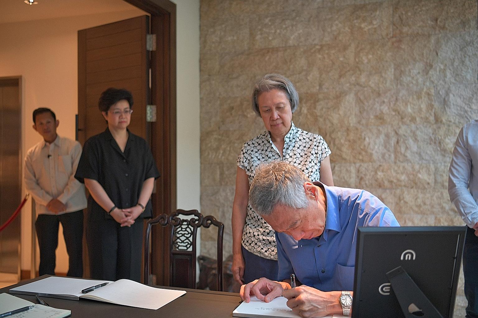 Prime Minister Lee Hsien Loong penning a condolence message at the wake of former chief justice Yong Pung How yesterday, as Mr Yong's daughter, Ms Yong Ying-I, looks on. Behind him is PM Lee's wife Ho Ching. They were among a stream of people, includ