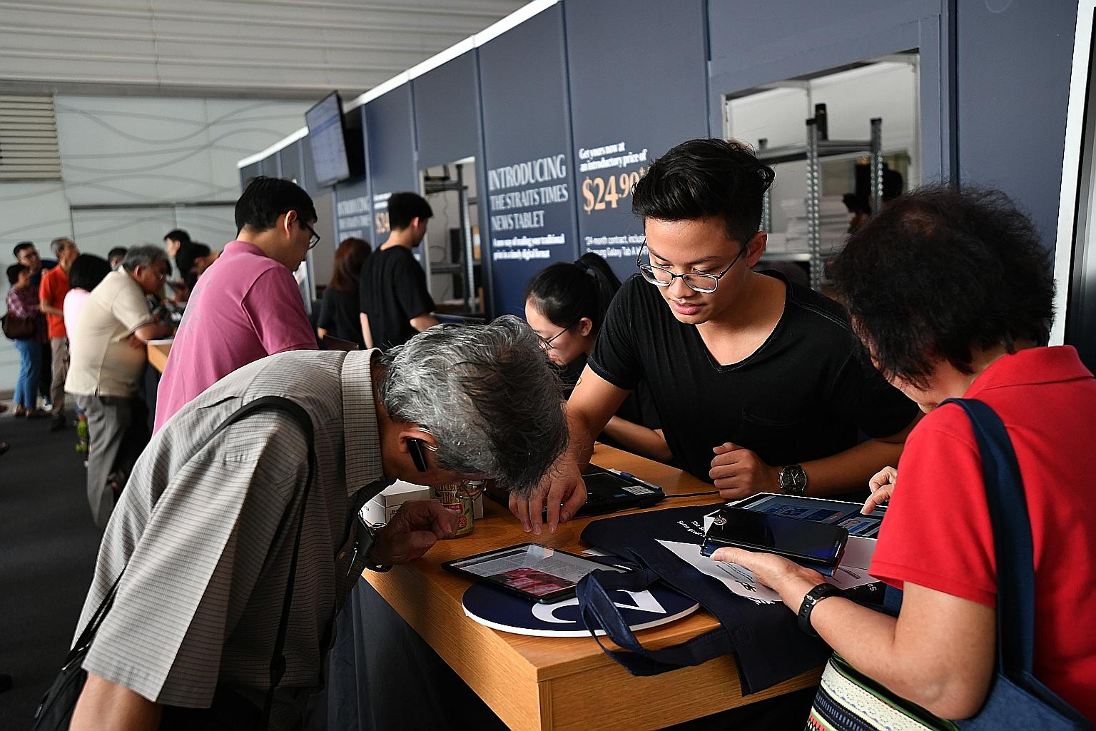 Subscribers collecting their Samsung tablets, preloaded with the ST app, at Plaza Singapura on Dec 20. Within three weeks of the Dec 18 launch, there were more than 5,000 sign-ups, over half of them from new subscribers.