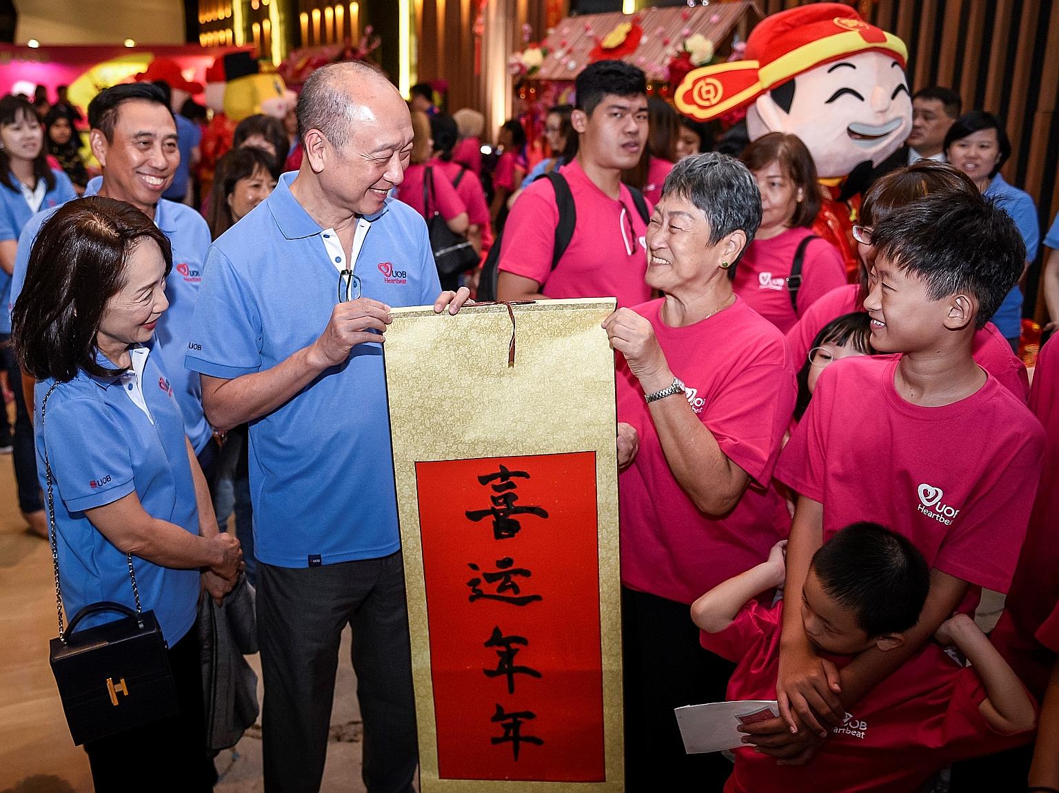 Mr Wee Ee Cheong (second from left), deputy chairman and chief executive of UOB, and Mrs Wee, seen here with Mr Eric Tham (back row, far left), head of UOB's group commercial banking, presenting a Chinese calligraphy scroll for Chinese New Year to a 