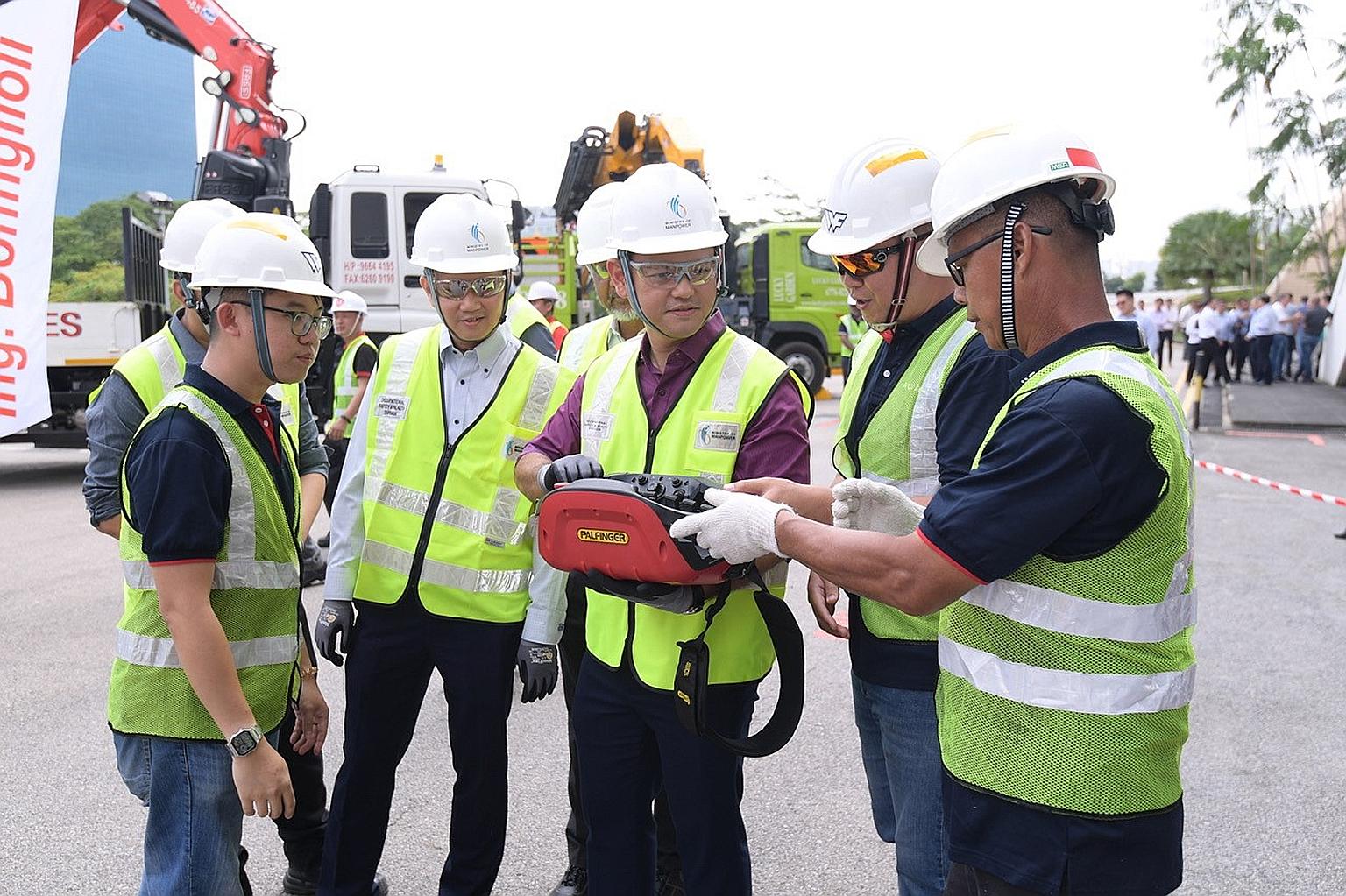 Minister of State for Manpower Zaqy Mohamad trying his hand at operating a lorry crane remotely via a control box. The Ministry of Manpower and the Workplace Safety and Health Council will launch two new sets of guidelines on the safe use of lorry cr
