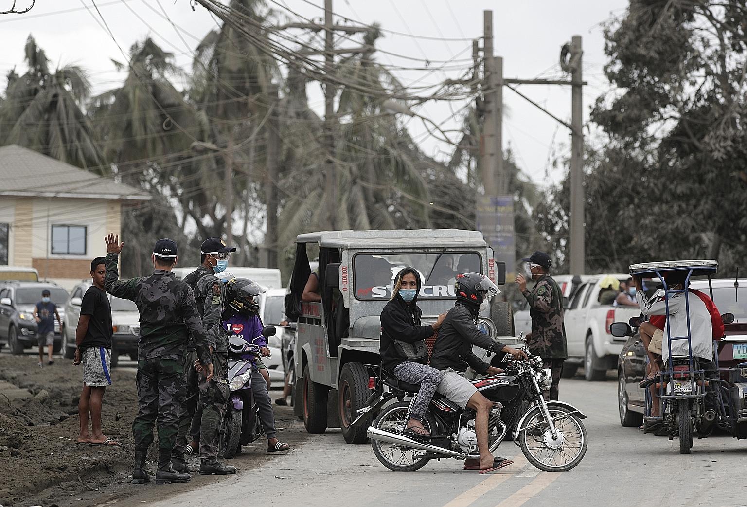 Police blocking a road to a village near Taal volcano yesterday. As the volcano has calmed slightly in the past 24 hours, the temptation to return has grown. PHOTO: ASSOCIATED PRESS