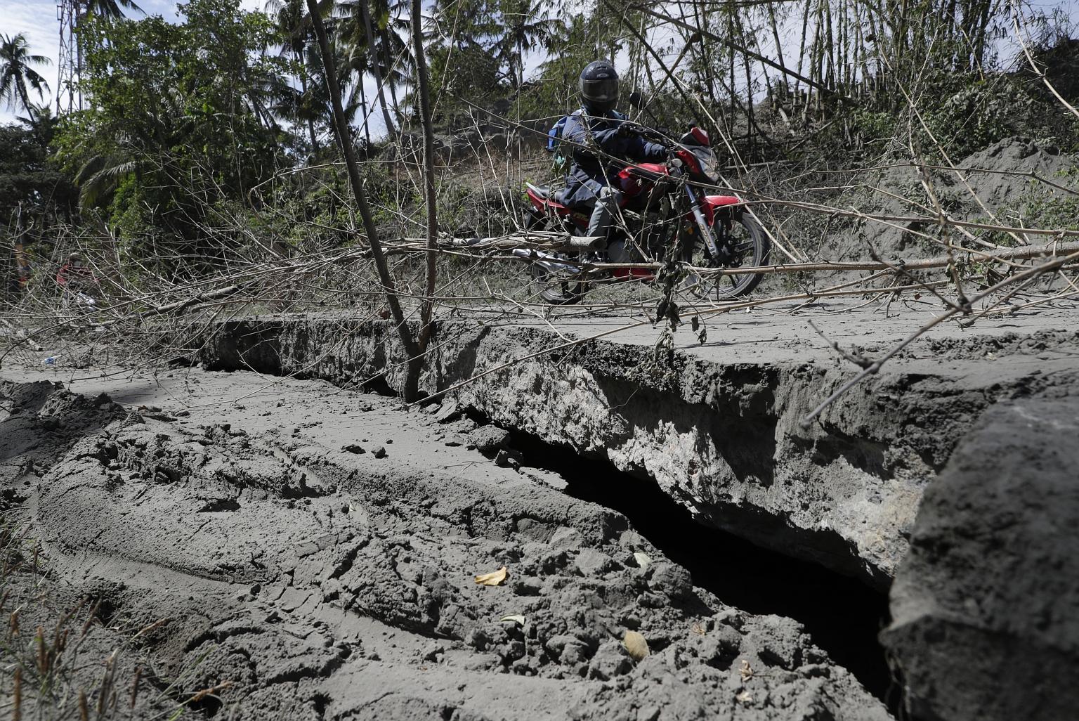 A motorcycle rider negotiating a crack in the road yesterday, after Taal volcano's eruption in the Philippines last weekend. PHOTO: ASSOCIATED PRESS